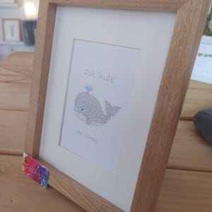 View from the right side of a framed image of a baby whale. The complete image consists entirely of handwritten words. In this image the words are hundreds of times the name of the baby.
Under the baby whale is written the date of the baptism.