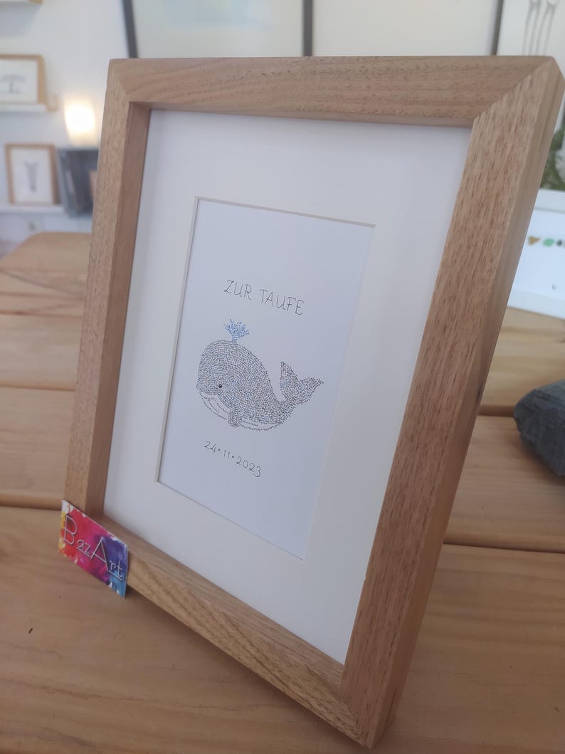View from the right side of a framed image of a baby whale. The complete image consists entirely of handwritten words. In this image the words are hundreds of times the name of the baby.
Under the baby whale is written the date of the baptism.