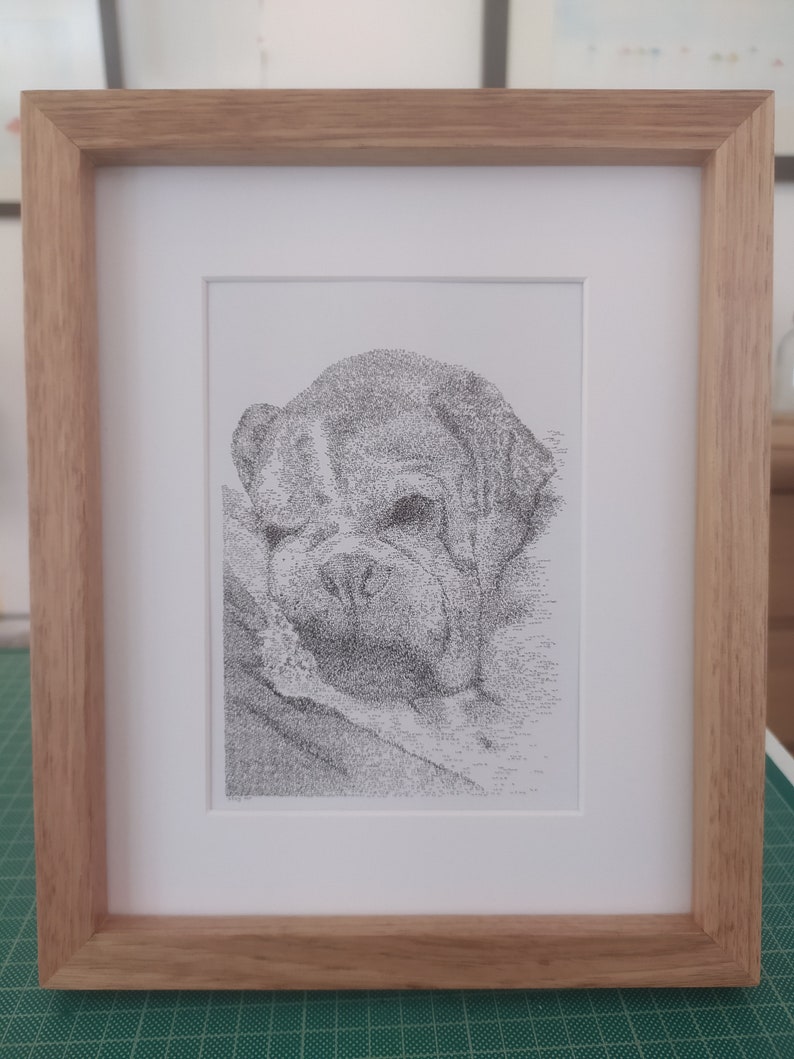 May include: A black and white pen and ink drawing of a bulldog's head, framed in a light wood frame.