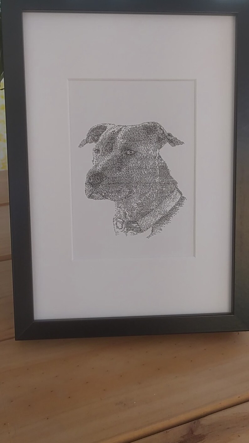 May include: A black and white framed print of a dog's head, created using a stippling technique.