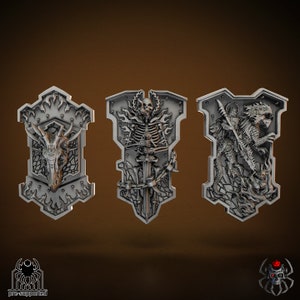 May include: Three silver metal shields with intricate designs. The first shield features a dragon head, the second a skeleton holding a sword, and the third a dragon with a knight on its back.
