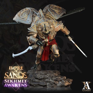 May include: A detailed miniature figurine of a warrior with golden armor and wings, holding a sword and a scimitar. The figurine is standing on a rocky base. The text "Empire of Sands Sekhmet Awakens" is visible below the figurine.