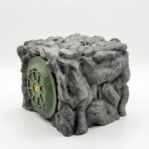 May include: A gray, rock-textured cube featuring a circular, olive green vault door embedded on one side. The door has a mechanical, wheel-like design with the number 101 printed in yellow at its center, resembling a fortified bunker entrance.