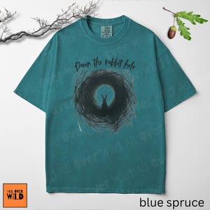 May include: Teal-coloured t-shirt featuring the phrase "Down the rabbit hole" above a rabbit graphic. The design is on a vintage-wash tee with a crew neck. The brand logo "All Over Wild" is in the bottom left corner. The shirt is a size XL.