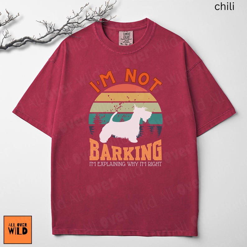 May include: A chili red short-sleeve t-shirt featuring a graphic of a white dog silhouette centered within a retro sunset circle. The text reads I'M NOT BARKING I'M EXPLAINING WHY I'M RIGHT in orange and white lettering against a forest background.