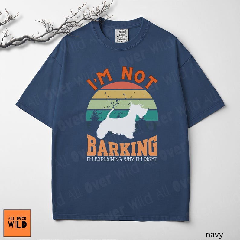 May include: A navy blue short-sleeve t-shirt featuring a graphic of a white dog silhouette against a sunset background. The text reads I'M NOT BARKING I'M EXPLAINING WHY I'M RIGHT in orange and white lettering. The shirt has a crew neckline.