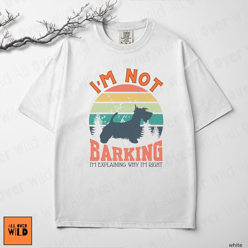 May include: A white short-sleeve t-shirt featuring a graphic of a black Scottish Terrier silhouette against a retro sunset circle. The text reads I'M NOT BARKING I'M EXPLAINING WHY I'M RIGHT in orange and black lettering with a forest background.