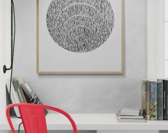 May include: A black and white abstract print of a circle with concentric rings of lines. The print is framed in a light wood frame and is hanging on a white wall. A red metal chair is in the foreground.