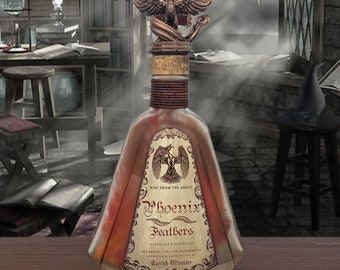 May include: A decorative bottle with a bronze phoenix topper. The bottle has a label that reads "Phoenix Feathers" and "Rise From The Ashes". The bottle is filled with a reddish liquid and has a cork stopper. The background is a dimly lit room with books and a desk.