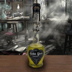 May include: A decorative glass bottle with a yellow liquid inside. The bottle is labeled "Basilisk Venom" and has a silver snake wrapped around the neck. The bottle is sealed with a black stopper.