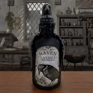 Pode incluir: Uma garrafa de vidro preto com um design de corvo no rótulo. O rótulo diz "Raven Feathers" e "Ethically Sourced" em uma fonte gótica. A garrafa tem uma rolha em forma de corvo preto.