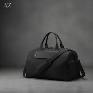 May include: A black duffel bag with a shoulder strap and top handles. The bag has a rectangular shape with a side pocket and a small, rectangular patch on the front. The letters "AZ" are in the upper left corner.