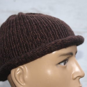 Op de afbeelding: Een bruine gebreide beanie met een omgeslagen rand. De beanie is gemaakt van zacht, getextureerd garen.