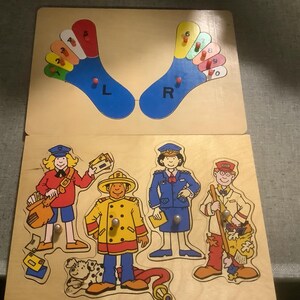 Puede incluir: Juego de rompecabezas de madera. La sección superior presenta dos piezas azules en forma de pie con dedos numerados y las letras "L" y "R". Debajo, un rompecabezas con figuras de un cartero, bombero, policía y jefe de tren.
