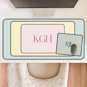 May include: A rectangular desk mat featuring a light blue and white striped pattern, a yellow and white striped inner rectangle, and a pink and white striped center rectangle with the letters KGH. A smaller mouse pad with RJ and a gray mouse.