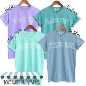 May include: Four t-shirts in different colours with the text "BEACH BUM" in white outlined letters. The colours are violet, seafoam, chalky mint, and ice blue.