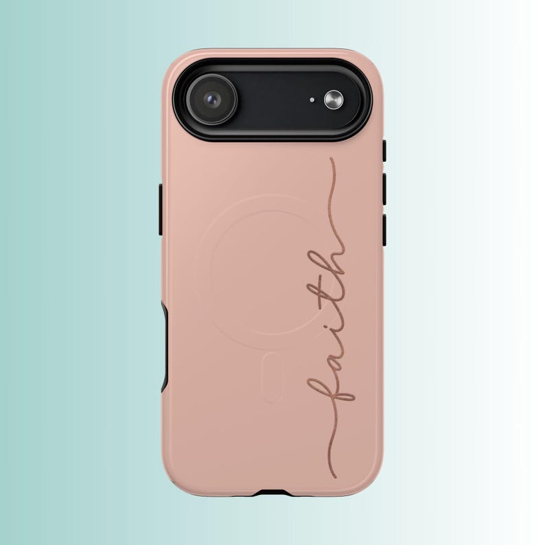 Pu&ograve; includere: Una custodia per telefono rosa antico con un alloggiamento per fotocamera nero. La parola "faith" &egrave; scritta in corsivo sulla custodia. La custodia ha una finitura liscia e un design protettivo.