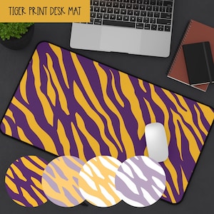 May include: A rectangular desk mat with a purple and gold tiger stripe pattern. The mat has a black border and the words "TIGER PRINT DESK MAT" in a yellow banner. A white computer mouse is on the mat.