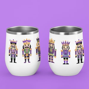 Puede incluir: Dos vasos de vino de acero inoxidable blanco con un diseño colorido de figuras de cascanueces con trajes morados y dorados.