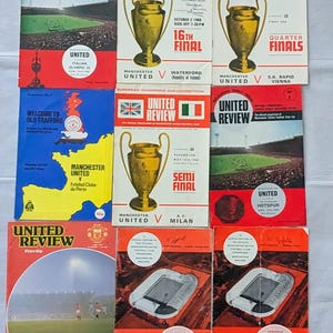 Op de afbeelding: Een verzameling vintage "United Review" voetbalwedstrijdprogramma's. De covers tonen het logo van het team, stadion scènes en details van de European Champions Cup competitie. De programma's zijn in rood, wit en zwart.