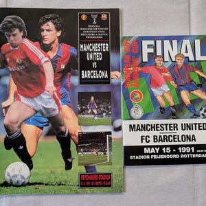May include: Two vintage soccer match programs. The larger program features players in red and blue uniforms, with the text "Manchester United vs Barcelona." The smaller program reads "Final" and "Manchester United FC Barcelona."