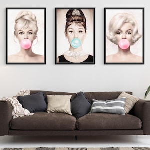 May include: Three black framed prints of famous women blowing bubble gum. The women are Audrey Hepburn, Brigitte Bardot, and Marilyn Monroe. The prints are in a vintage style with a sepia tone.