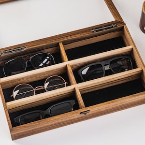 Handcrafted wooden sunglasses case for 6 glasses with a stylish design and glass lid so you can always see your glasses, even when box is closed. Each compartment has a felt lining to protect your glasses from scratching.