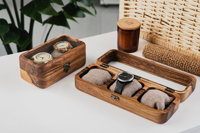 Unique Wood watch box for watches, featuring rounded corners, a sleek, treated wood texture, and a glass lid for constant visibility. Customize the glass lid with your own engraving.