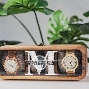 Unique Wood watch box for watches, featuring rounded corners, a sleek, treated wood texture, and a glass lid for constant visibility. Customize the glass lid with your own engraving.