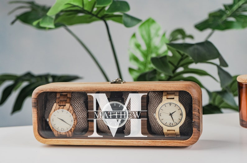 Unique Wood watch box for watches, featuring rounded corners, a sleek, treated wood texture, and a glass lid for constant visibility. Customize the glass lid with your own engraving.