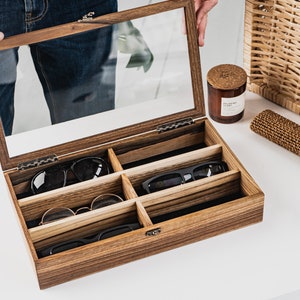 Handcrafted wooden sunglasses case for 6 glasses with a stylish design and glass lid so you can always see your glasses, even when box is closed. Each compartment has a felt lining to protect your glasses from scratching.