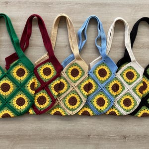 May include: Six crocheted tote bags with sunflower designs in various colors, including green, red, beige, blue, white, and black.