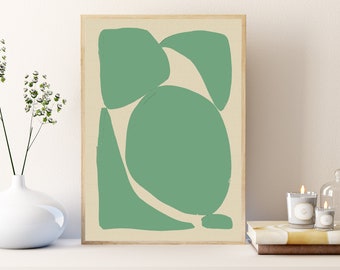 May include: Abstract art print featuring a light green design on a beige background, framed in a natural wood. The artwork showcases organic shapes, creating a modern and minimalist aesthetic. The print is displayed on a white surface, with a vase and candles in the background.