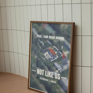 May include: A framed print with a blurred image of a house and the text "Psst, I see dead people - NOT LIKE US - Kendrick Lamar".