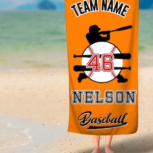 Puede incluir: Toalla de playa naranja con una silueta de un jugador de béisbol, una pelota de béisbol con el número 46 y el texto "TEAM NAME NELSON Baseball".