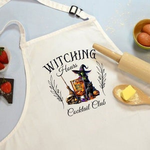 May include: White kitchen apron with a black and green illustration of a witch holding a glass of "Wicked Witch Whiskey" and a broom. The text "Witching Hours Cocktail Club" is printed on the apron.