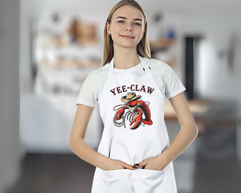 May include: White apron with a red lobster wearing a cowboy hat and the text "Yee-Claw".