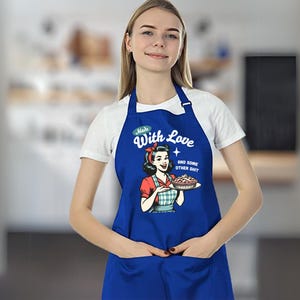 Puede incluir: Delantal azul real con un dise&ntilde;o retro de una mujer sosteniendo un pastel. El delantal tiene el texto "Made With Love and Some Other Shit". Cuenta con un bolsillo frontal y una correa para el cuello.