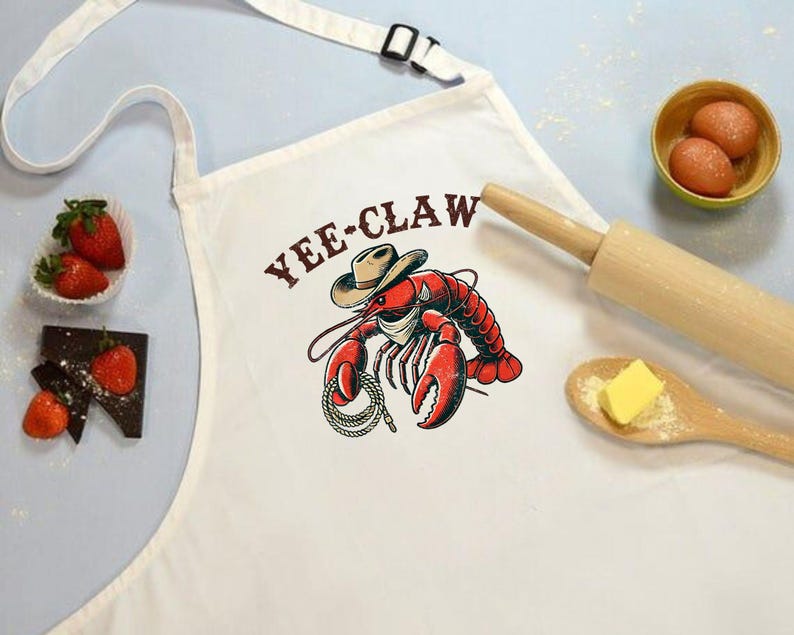 May include: White apron with a red lobster wearing a cowboy hat and the text "Yee-Claw".