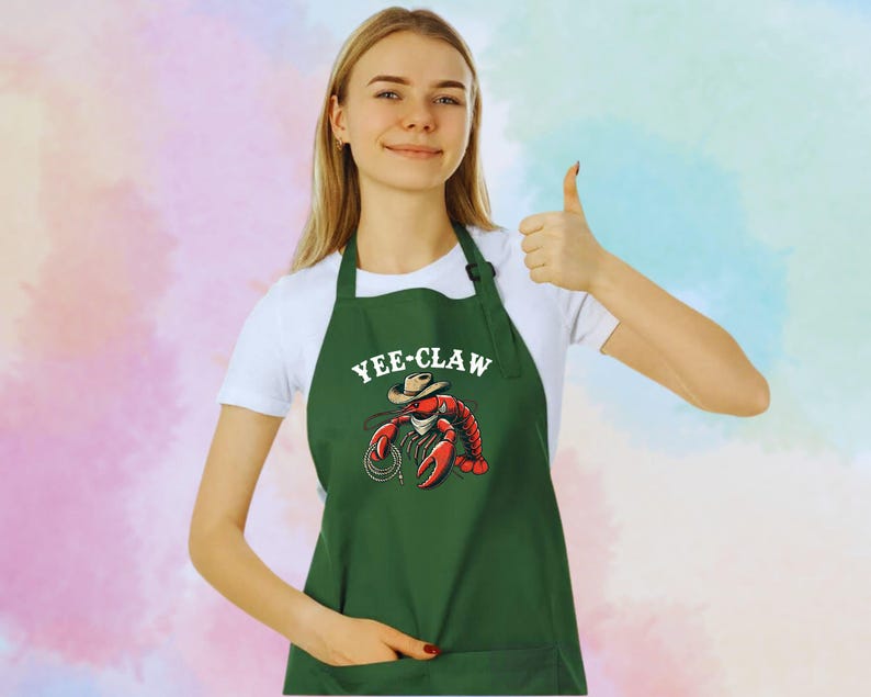 May include: Green apron featuring a cartoon lobster wearing a cowboy hat with the text "Yee-Claw".