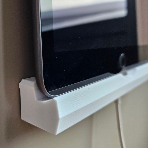 Minimalistic iPad wall mount shelf, adhesive with integrated charging cable holder. The Padholder 3000: universal tablet wall mount.