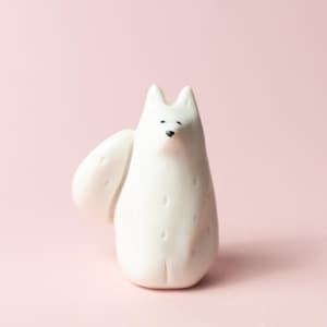 Könnte beinhalten: Weiße Keramikfigur eines Fuchses mit schlichtem Design. Der Fuchs hat einen runden Körper und einen kleinen, spitzen Schwanz.