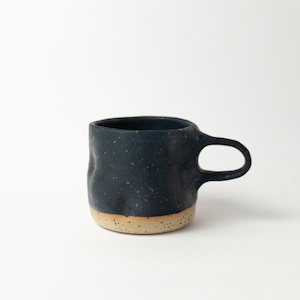 Può includere: Tazza in ceramica blu scuro con smalto maculato. La tazza ha un corpo arrotondato, un manico e una base beige naturale. Perfetta per caffè o tè, questa tazza è un'aggiunta unica a qualsiasi cucina.