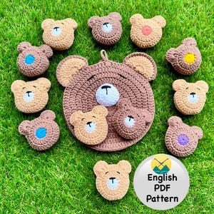 以下が含まれることがあります： 茶色とベージュの色合いで、白と黒の顔のディテールが施された、かぎ針編みのクマの形をしたアイテムのコレクション。大きな鍋つかみ、小さなコースター、青、ピンク、または黄色の中心を持つ丸いアイテムが含まれています。緑色の表面にあります。