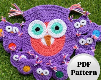 May include: A crocheted purple owl-shaped item with a large face and multiple smaller owl shapes around the perimeter. The owl's face features white, teal, and black eyes, with an orange beak. The text "PDF Pattern" is in a white circle.