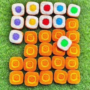 May include: A collection of crocheted squares in various colors, including orange, yellow, red, blue, green, and purple. The squares are arranged in a grid pattern, with some squares missing. The squares are all the same size and have a white border.