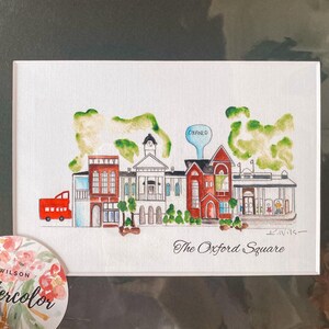 Puede incluir: Pintura acuarela de una plaza de pueblo con edificios, árboles y un autobús rojo. El texto "The Oxford Square" está escrito debajo de la imagen.