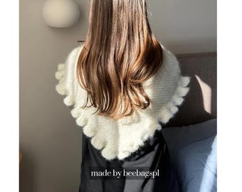 May include: A cream-colored, triangular knit shawl featuring a soft, fuzzy texture and a ruffled edge. The garment is draped over the shoulders and includes the text "made by beebagspl" printed in white at the bottom center of the image.