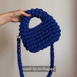 May include: A handmade, royal blue handbag with a thick, textured knit design. The bag features a rounded handle and a detachable shoulder strap. The text "made by beebagspl" is visible at the bottom of the image.