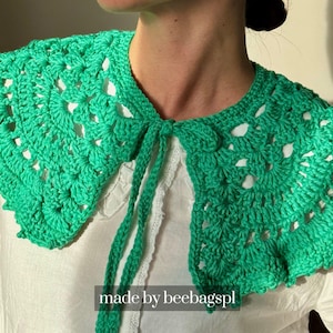 May include: A bright green, crocheted collar with a scalloped edge and tie closure. The collar is worn over a white blouse. The text "made by beebagspl" is visible at the bottom of the image.